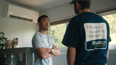 photo of a contractor talking to a customer in front of a heat pump