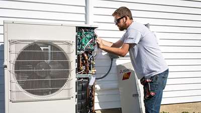 photo of a worker installing a heat pump