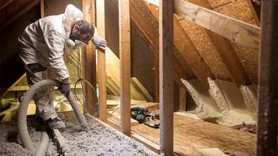 photo of an insulator adding blown insulation in an attic