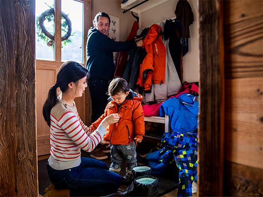 A family taking off their winter clothes in their home entryway