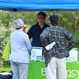 photo of a worker at an Efficiency Vermont booth at an event speaking with two people